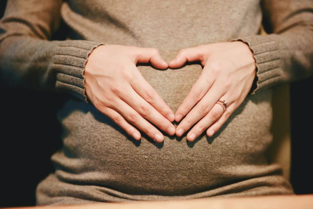 hypertension in pregnancy quiz - pregnant woman holding belling with a heart sign